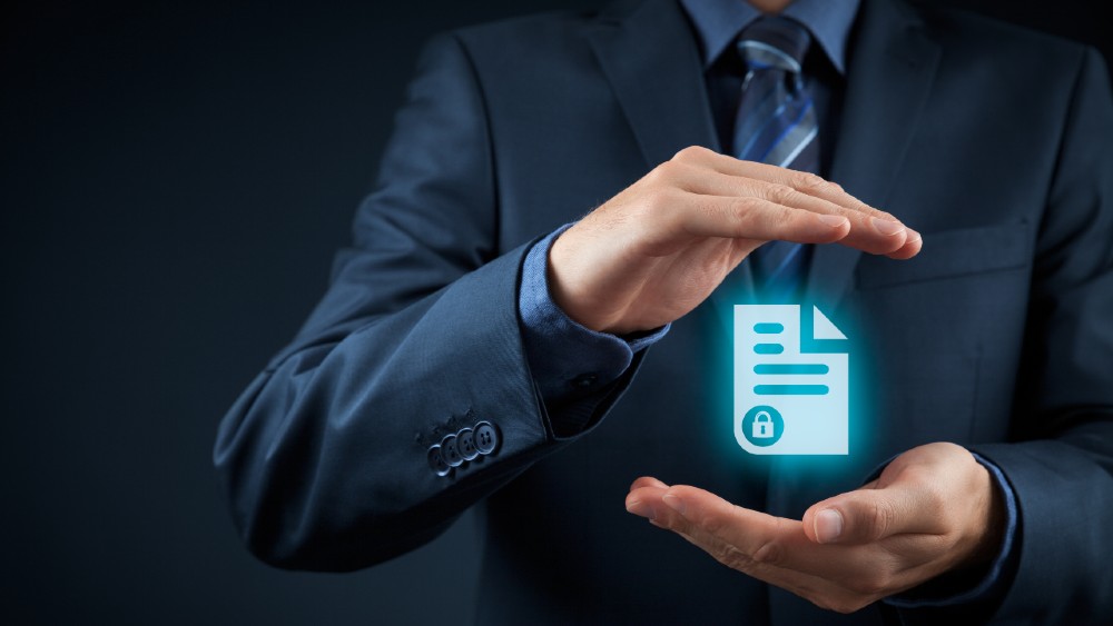 Poslovnež v obleki drži zaščiten digitalni dokument z ikono zaklepanja, kar simbolizira varstvo podatkov.